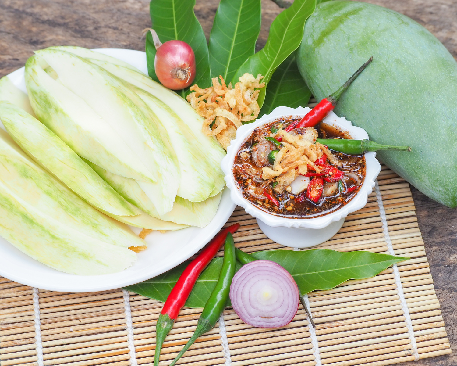Green Mango, slice mango with raw sour and sweet fish sauce in shrimp paste on old wooden table , Thai food , Selective focus