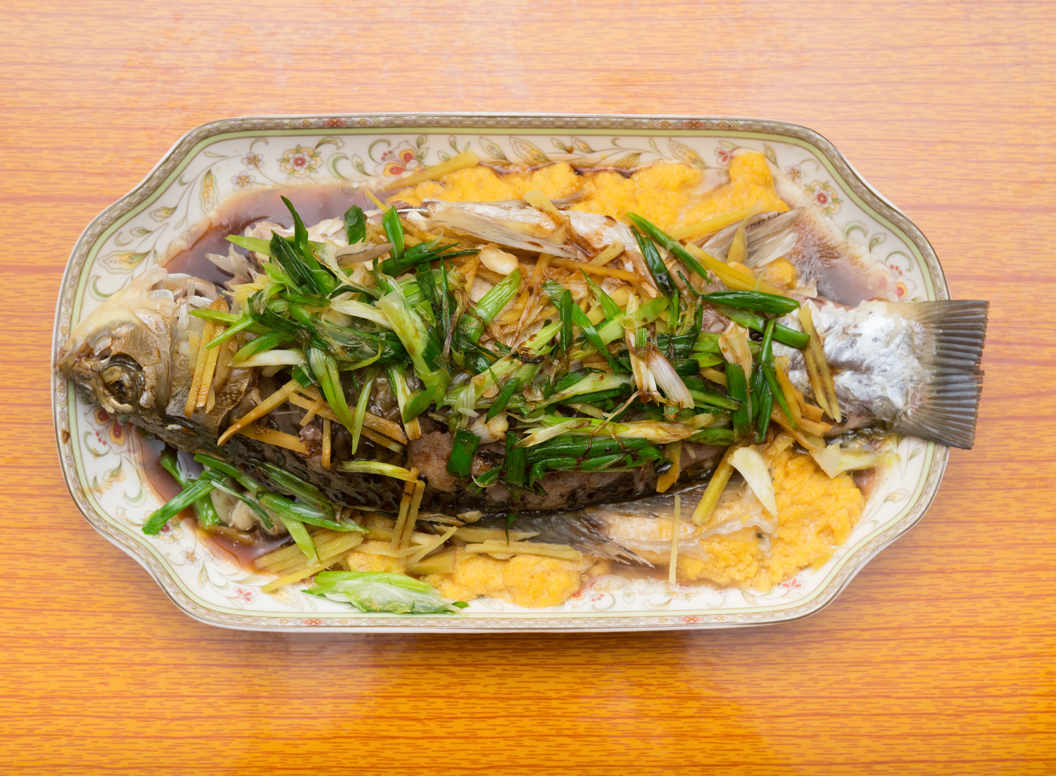 fresh steamed whole fish covered with herbs onions and sauce